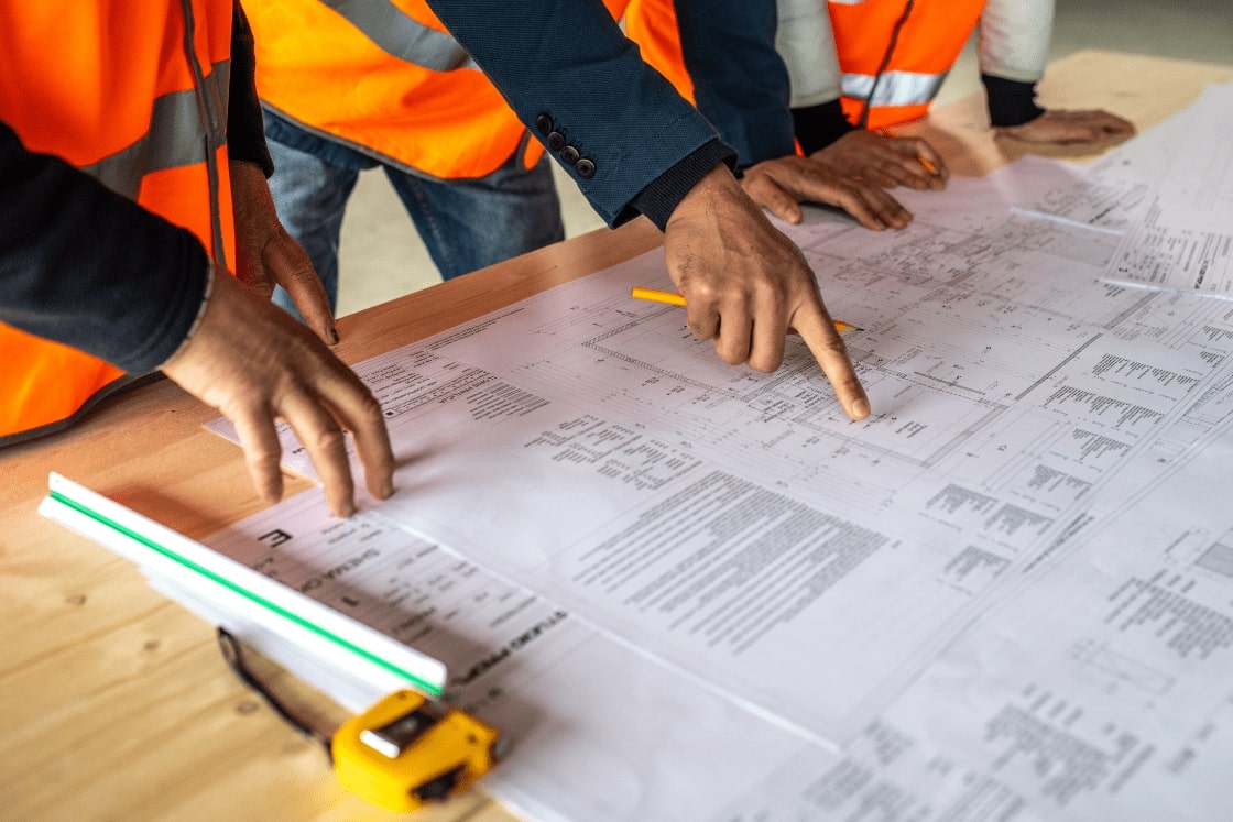 Expert cost estimators performing precise construction bid estimates with an open project plan on the table. Customized solutions for contractors and subcontractors
