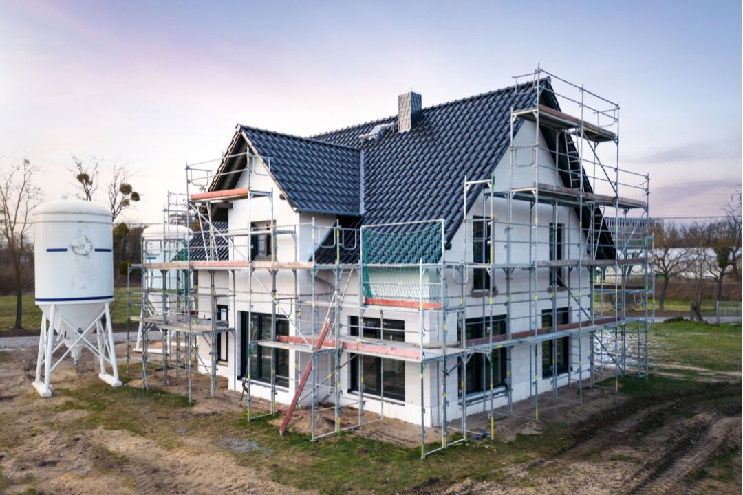 single residential home with construction materials, equipment, scaffolding, exterior and general requirementssymbolizing the need for accurate exterior finishes cost estimate and material takeoff services